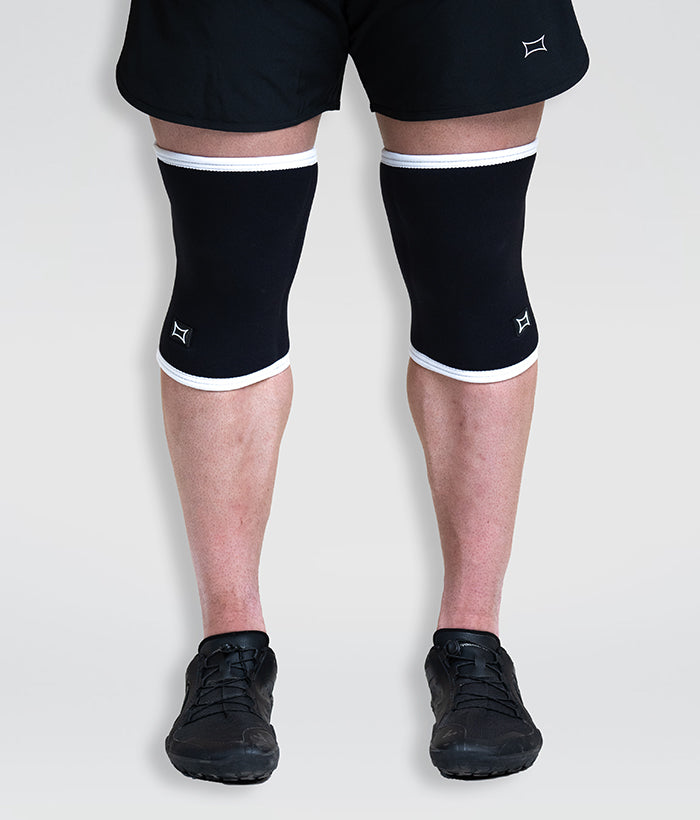 male wearing black and white full sized knee sleeves